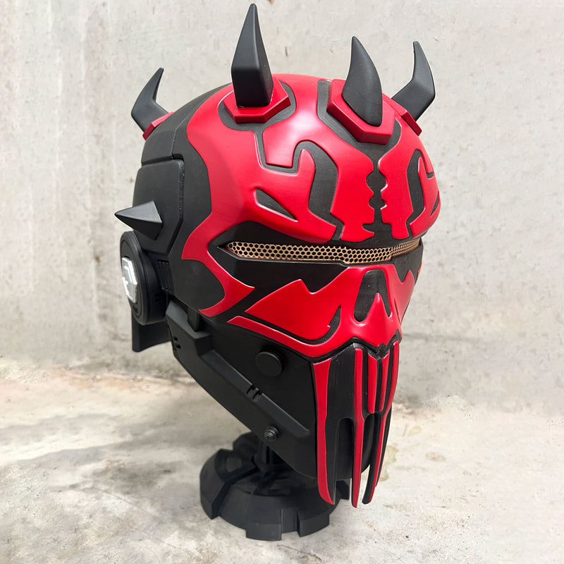 Red and black Darth Maul concept helmet with spikes on a textured surface