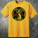 A yellow t-shirt with the Cobra Kai logo from the movie Karate Kid, featuring text and a cobra graphic.